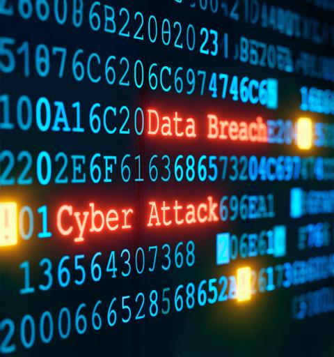 Highlighted words "Data Breach" and "Cyber Attack" in red on a black screen filled with code symbolize cybersecurity threats
