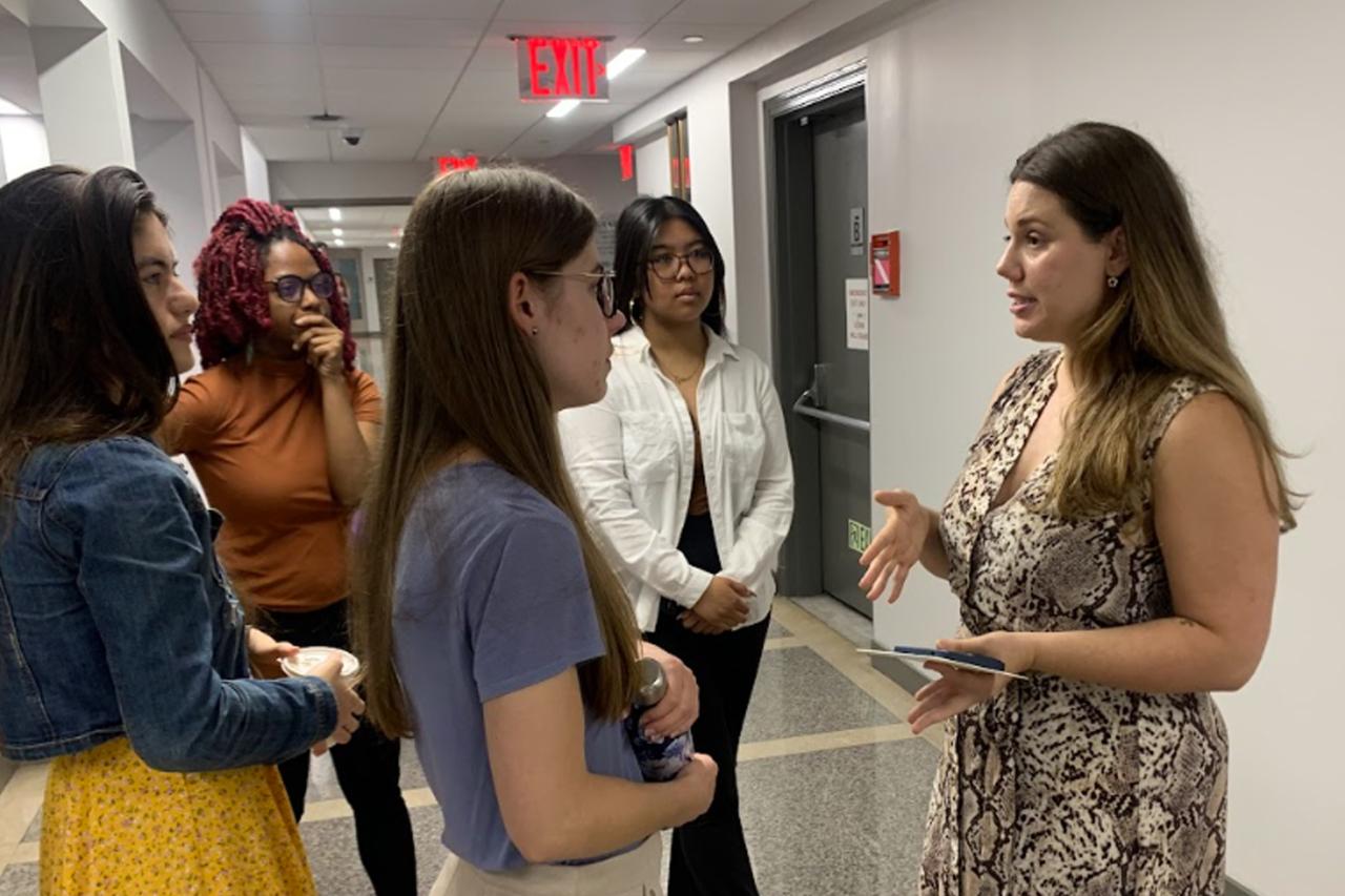 NYU SPS students gather at the Center for Publishing, Writing, and Media in a hallway to listen to instructions from a faculty member