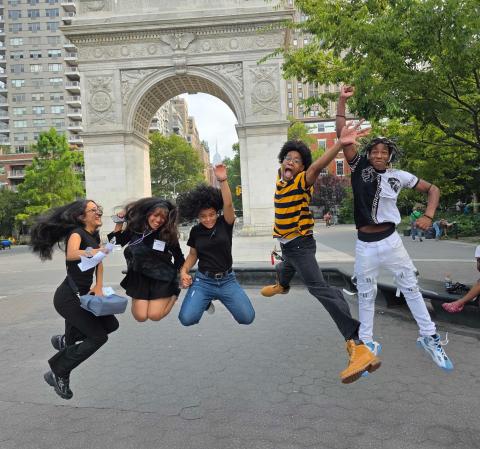 A group of NYU SPS Career Pathways Bridge Program students jumping in front of the Washington Square arch