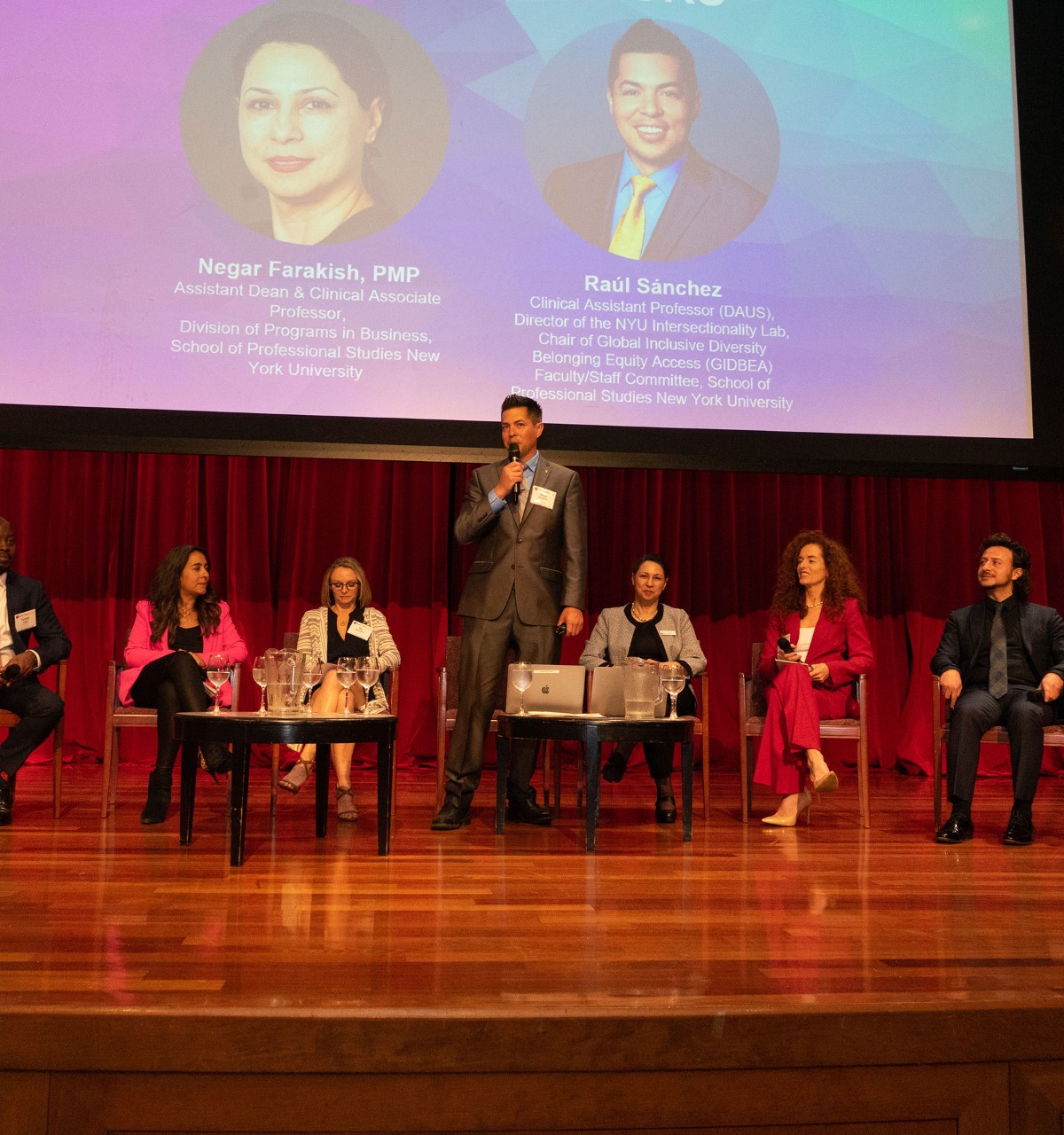 Panel discussion on stage with speaker presenting at NYU event