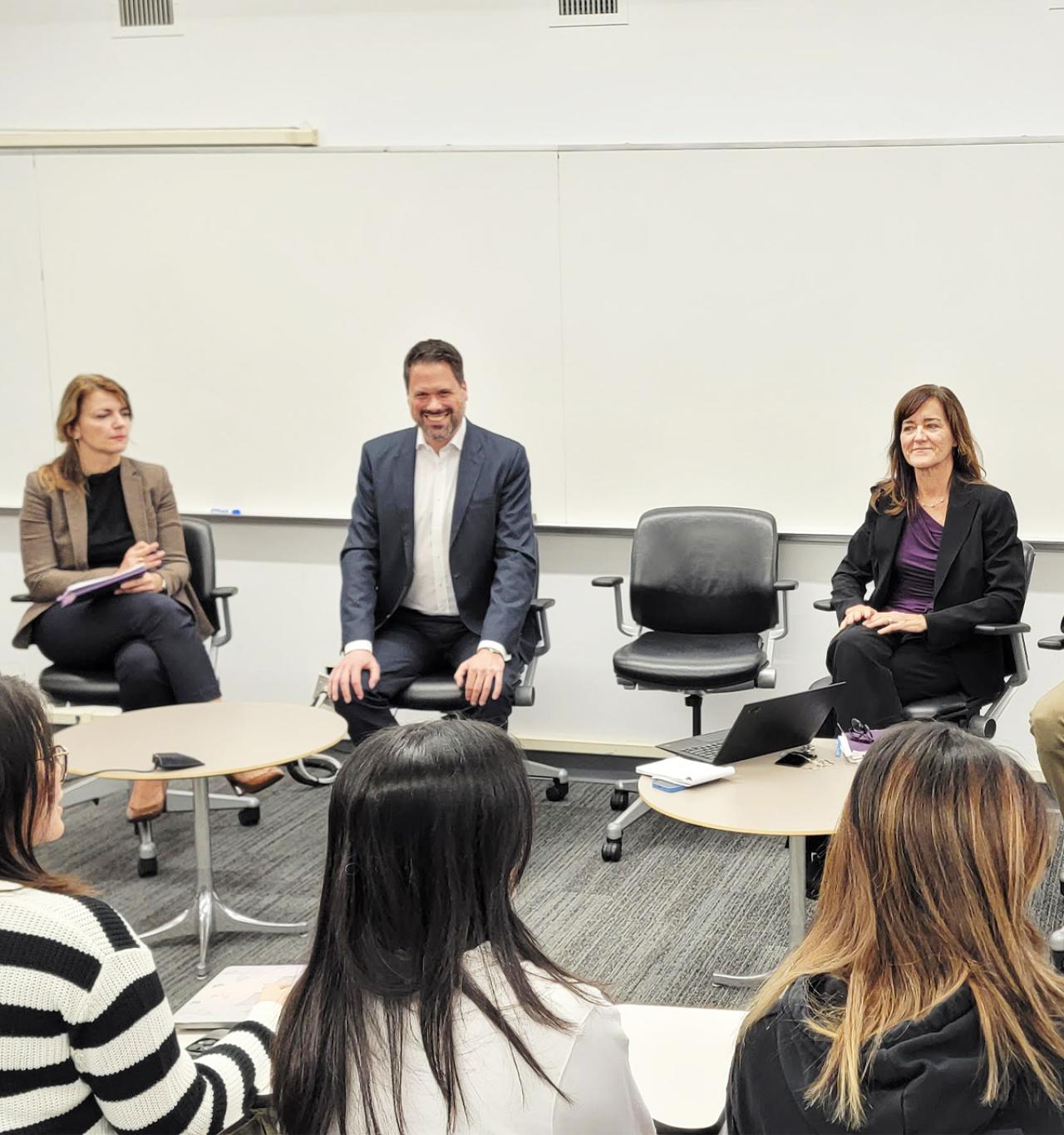 A small group huddles at office chairs in a classroom at the Future Forward Speaker Series.