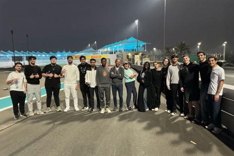 A group of NYU SPS students gather on a racing track for a photo
