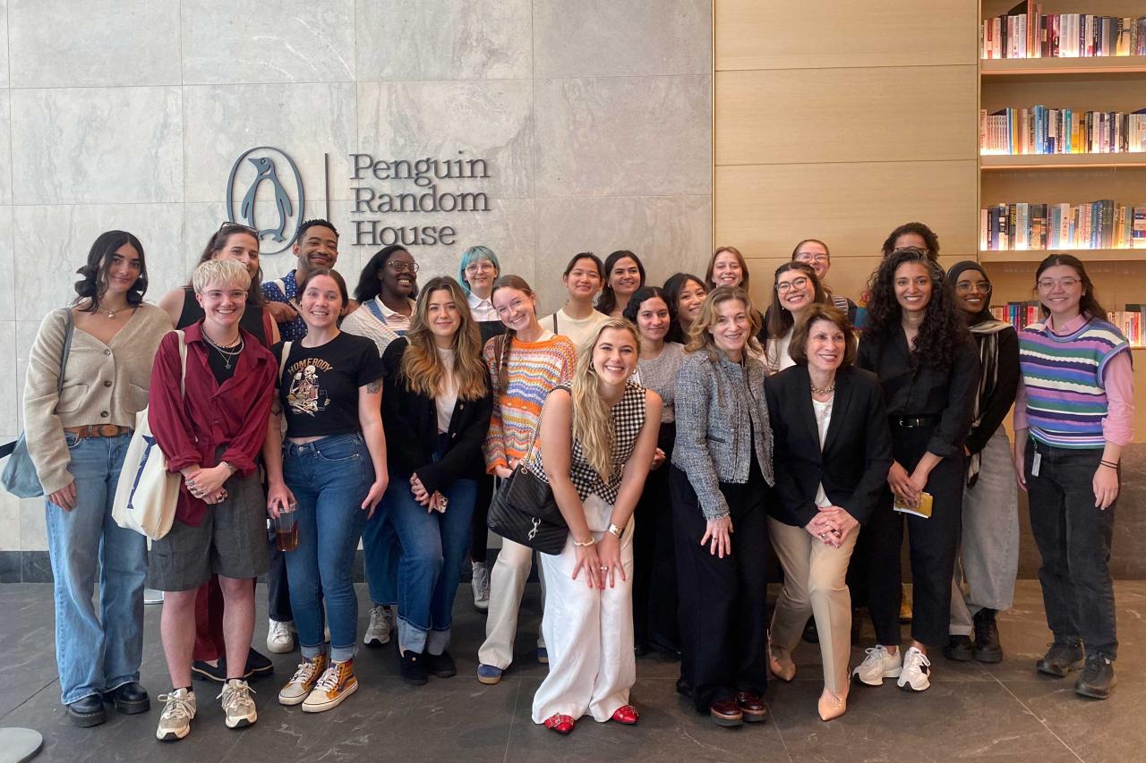 A group of diverse individuals smiles at the camera in front of a "Penguin Random House" sign.