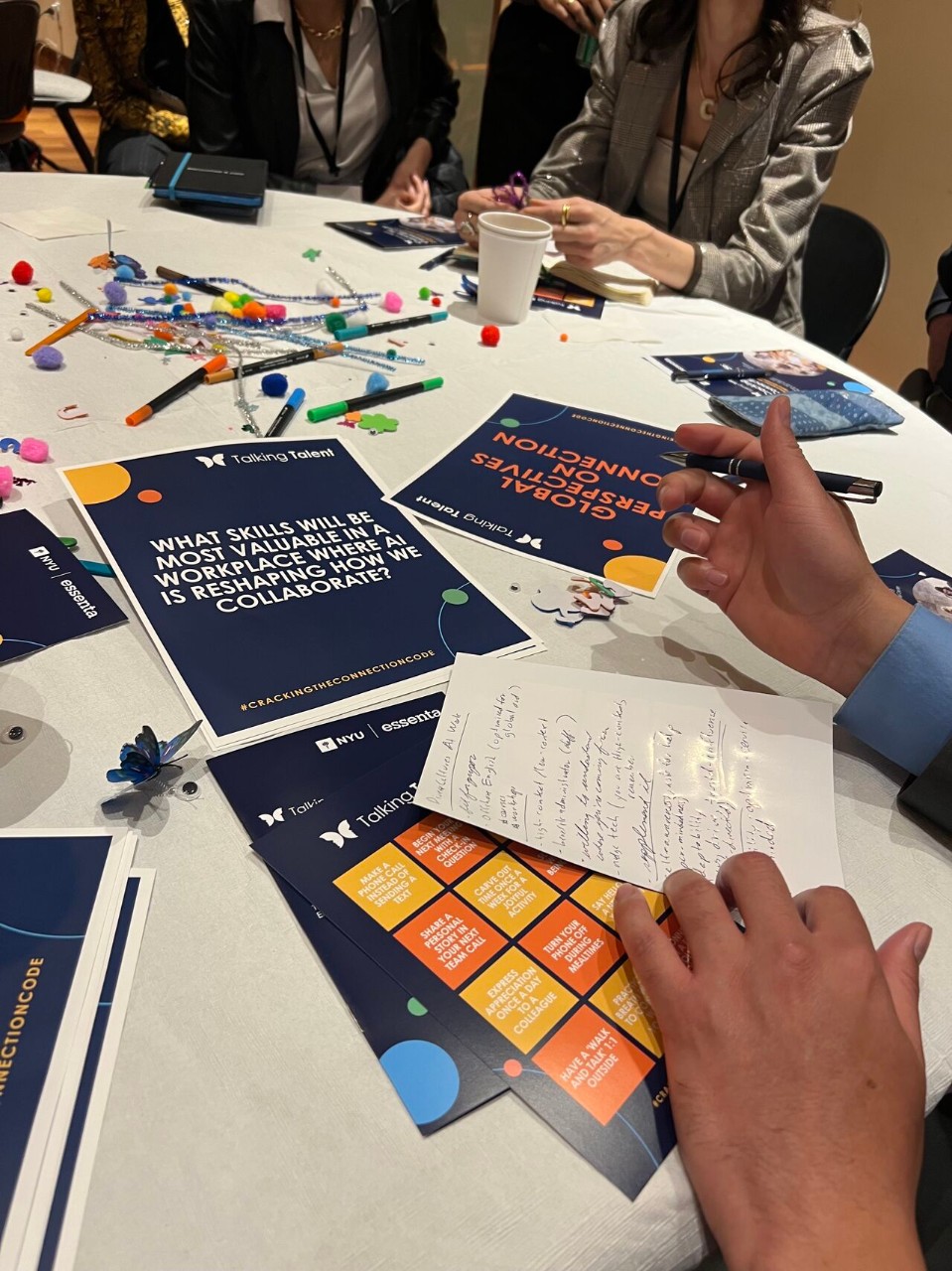 Close-up of a table during the World Café activity at the Cracking the Connection Code event, with discussion prompts, notes, and creative materials.