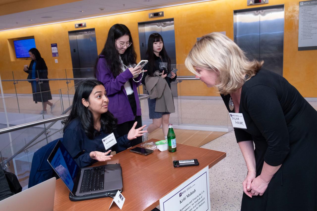 Kriti Mahtab speaks with a woman about Corporate Reputation and Trust in the US Healthcare Industry while two other women listen in the background.