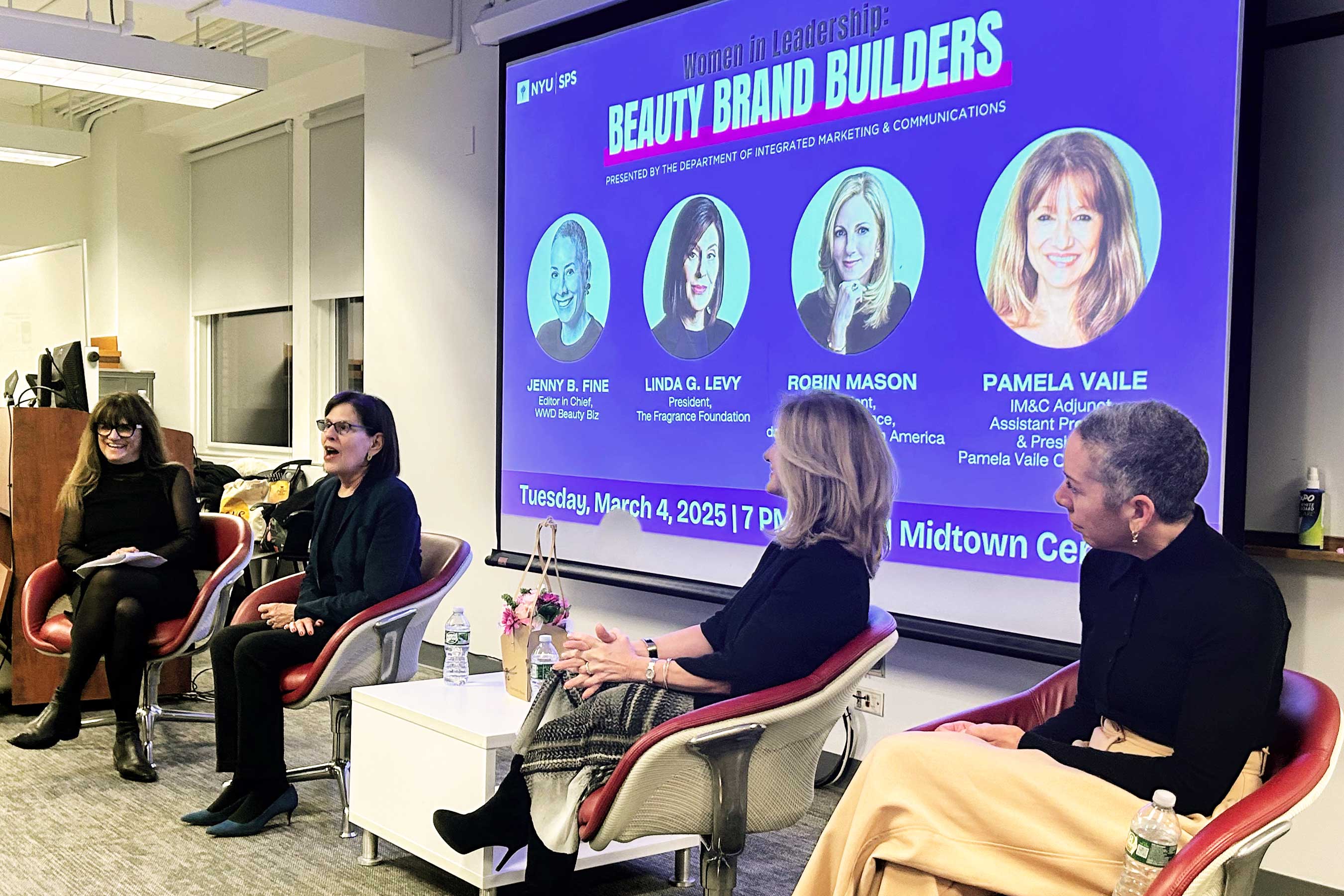 A panel discussion with four speakers seated in front of a screen displaying the event title "Women in Leadership: Beauty Brand Builders."