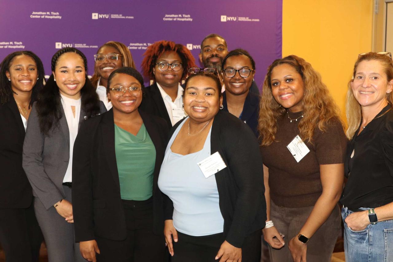 A group of ten people smiling in front of a purple background with logos and text.