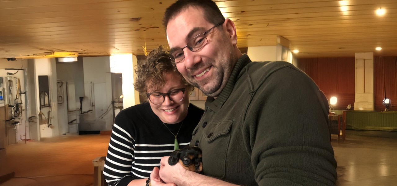 Nick Truxal, NYU SPS Division of Programs in Business alumnus, poses for a photo with his partner and a small dog.