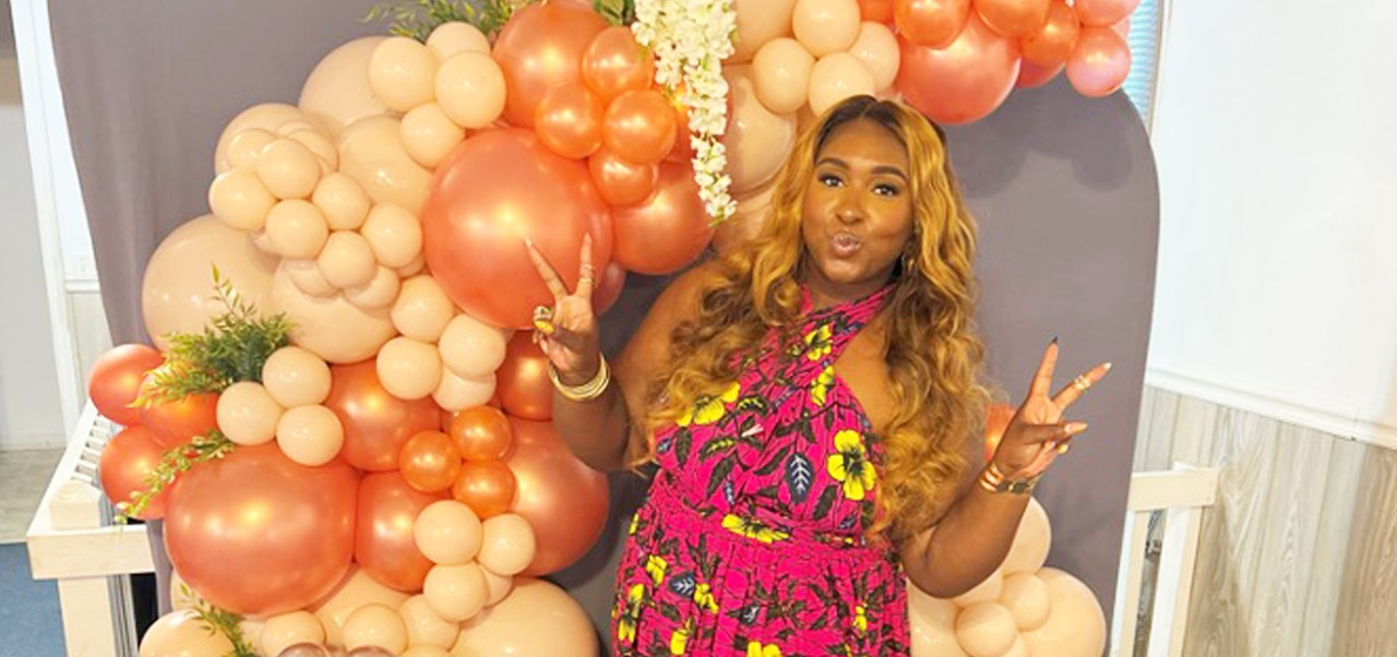 BA in Social Sciences alum Shakia Rose poses with peace signs in front of a balloon arch