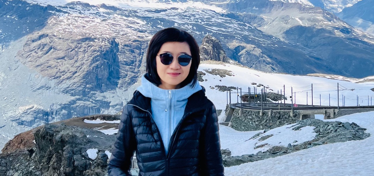 Dr. Jing Yang, Clinical Assistant Professor, Jonathan M. Tisch Center of Hospitality, NYU SPS poses for a photo amids a wintery mountainscape.