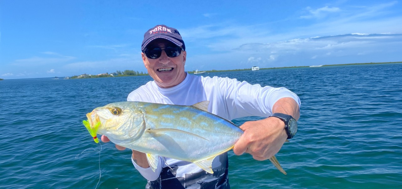 Paul Meadows smiles has he holds a large fish with the ocean in the background