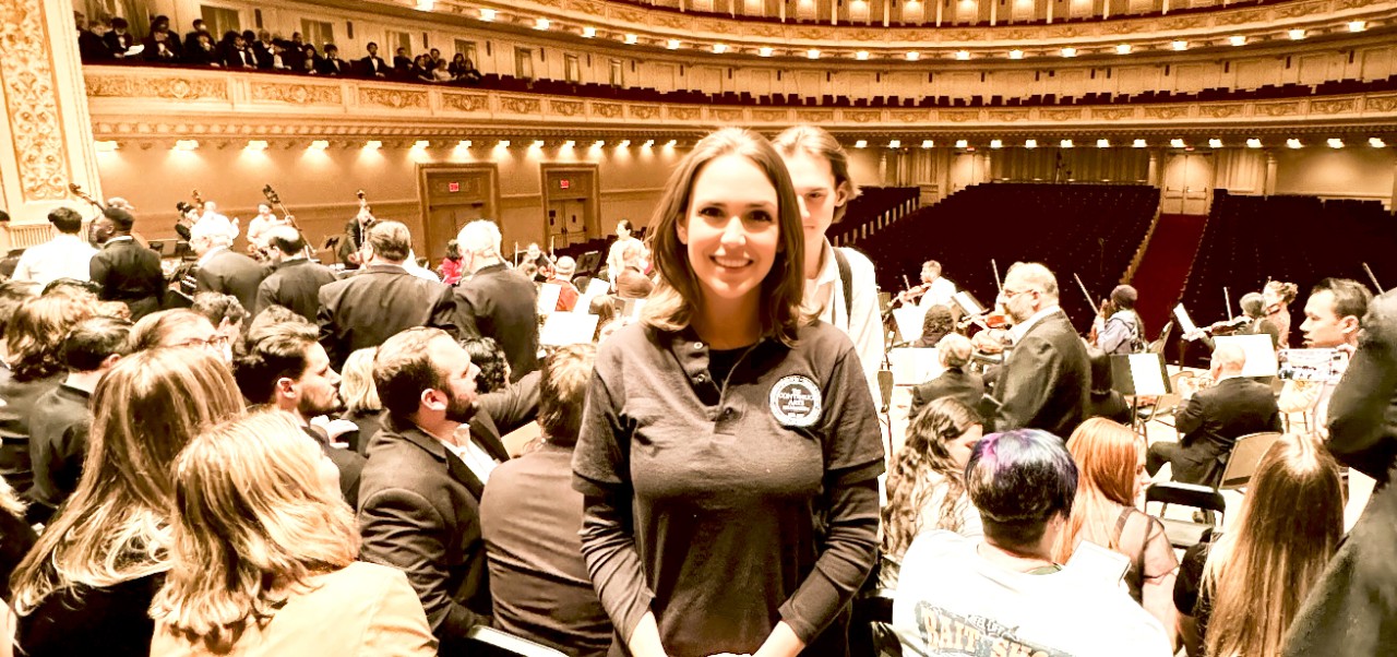  Stephanie Wright, Clinical Assistant Professor of Finance at the Schack Institute of Real Estate, NYU SPS, poses for a photo in front of a symphony orchestra