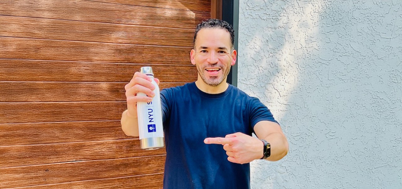 Franco Pedro Arguemdo, Center for Publishing and Applied Liberal Arts at NYU SPS student, points to an NYU SPS-branded water bottle.