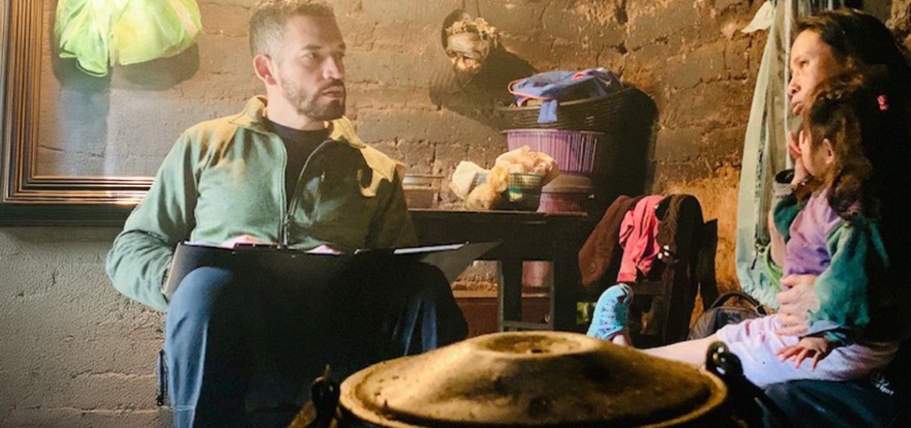 Franco Pedro Arguemdo, Center for Publishing and Applied Liberal Arts at NYU SPS student, engages with locals in their dimly lit home overseas.