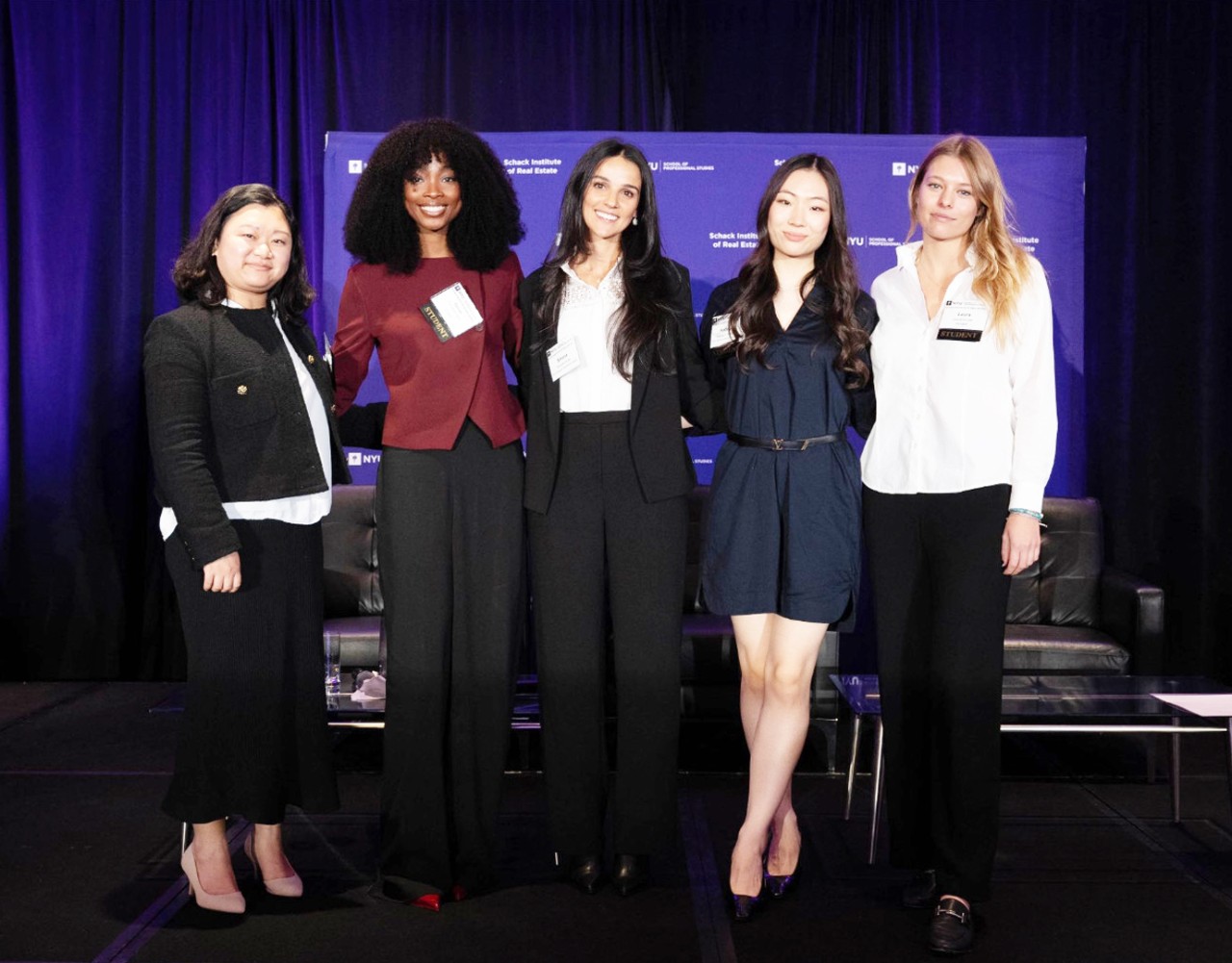 Katelynn Wisemann, student at the Schack Institute of Real Estate, NYU SPS, poses for a photo with classmates on a stage at a formal event.
