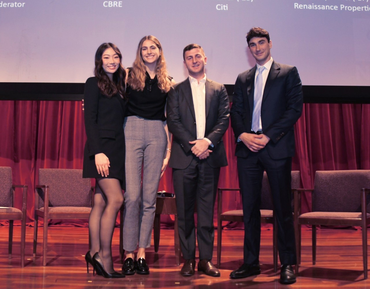 Katelynn Wisemann, student at the Schack Institute of Real Estate, NYU SPS, poses for a photo with classmates on a stage at a formal event.