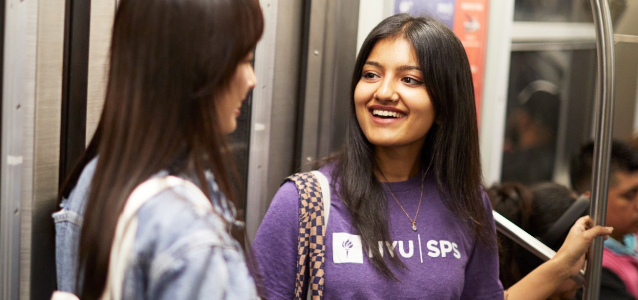 NYU SPS student Surabhi Achar smiles while talking with a friend on a New York City Subway train.