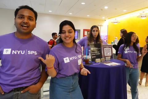 Students stand in front of a booth indoors.