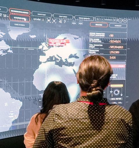NYU SPS students stand in front of a large screen with a map while experiencing emerging technology during a lesson
