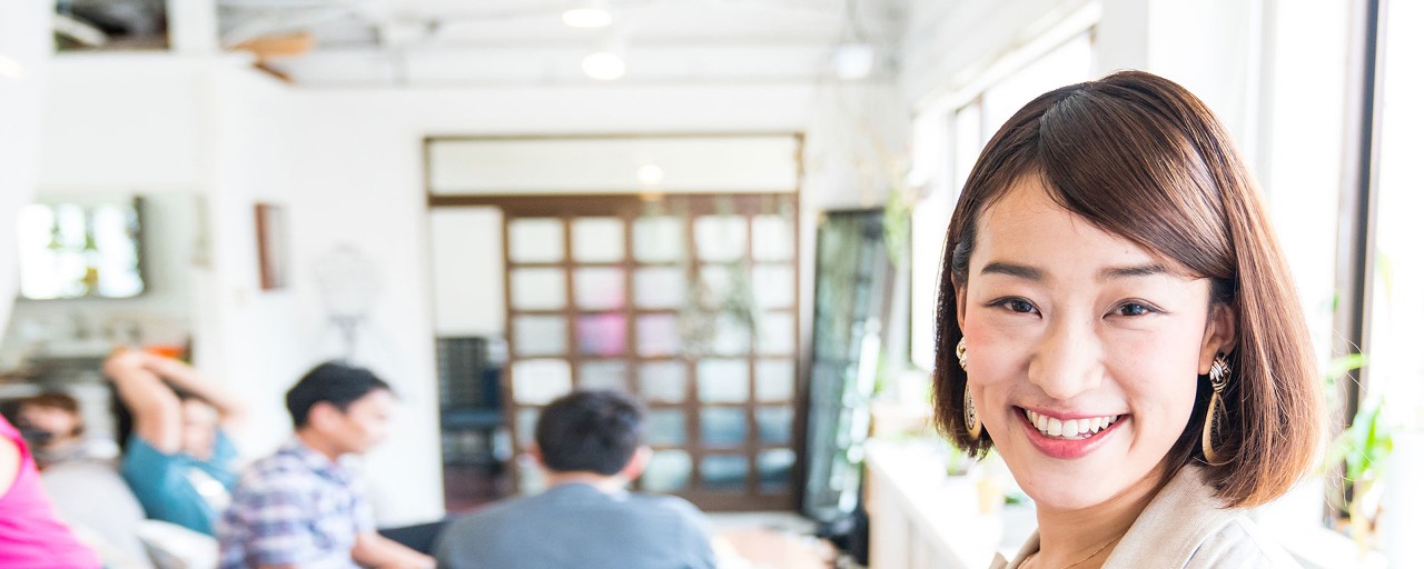 A woman smiles at the camera in while standing in a brightly lit, contemporary room.