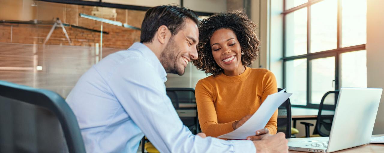 Two people at a table smile as they discuss the Certificate in Financial Planning program at NYU SPS.