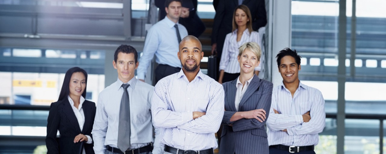 Several Certificate in Human Capital Management students stand together for a photo in an industrial office building