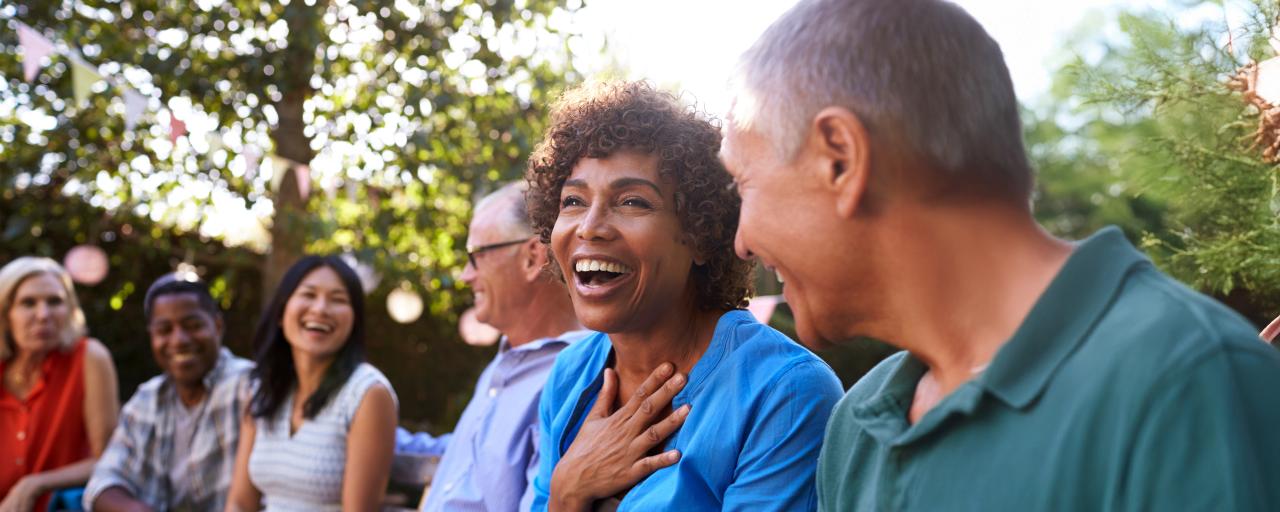 A woman laughs while seated in an audience at an outdoor event venue.