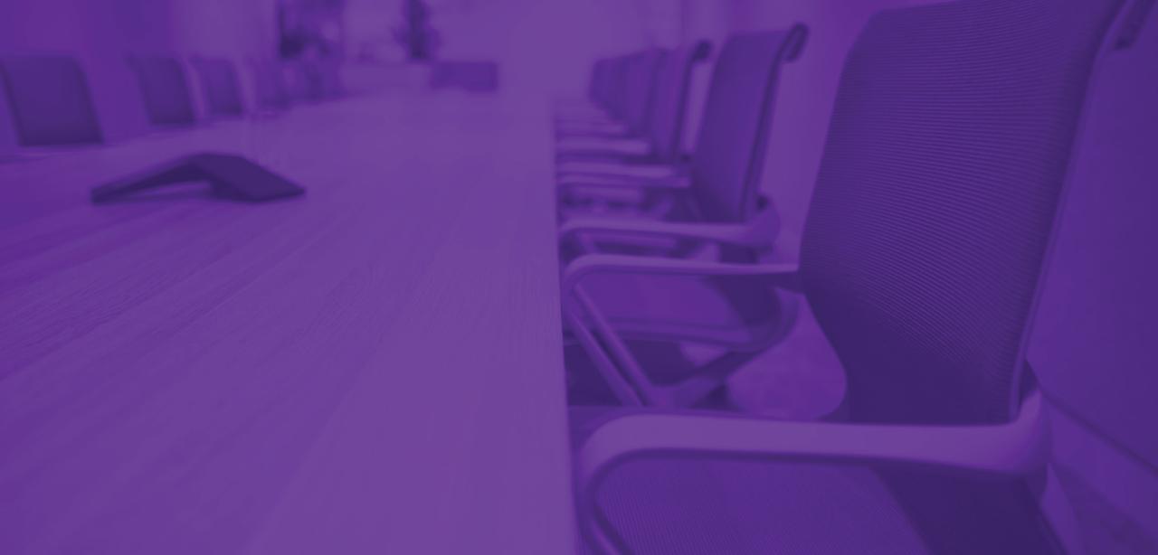Three colleagues walk down a New York City promenade, passing the window revealing a dimly lit lobby, blurred to suggest motion.