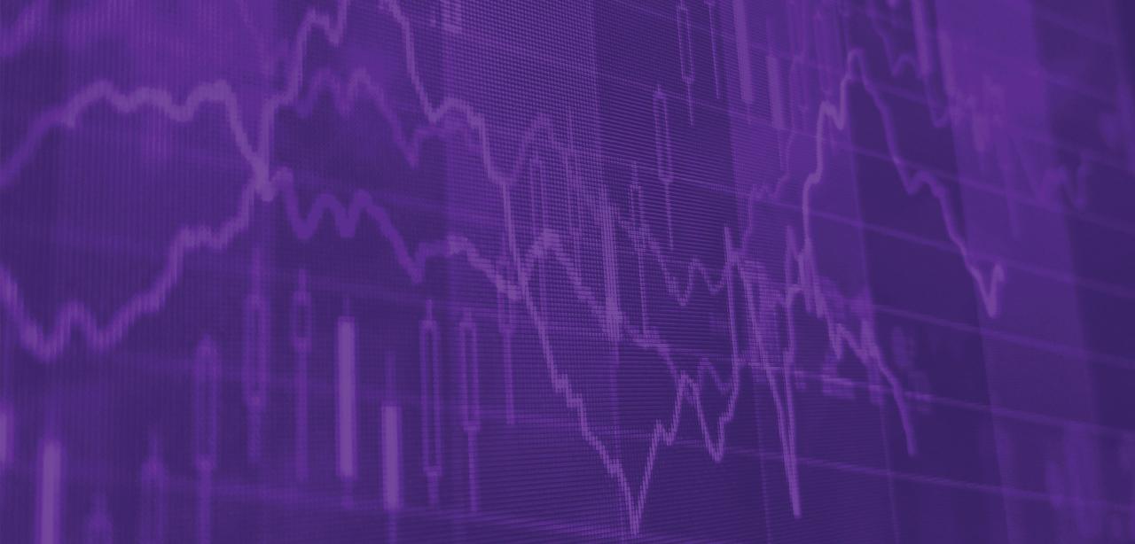 A man dressed in a blue suit checks his phone while crossing Wall Street in the financial district of New York City.