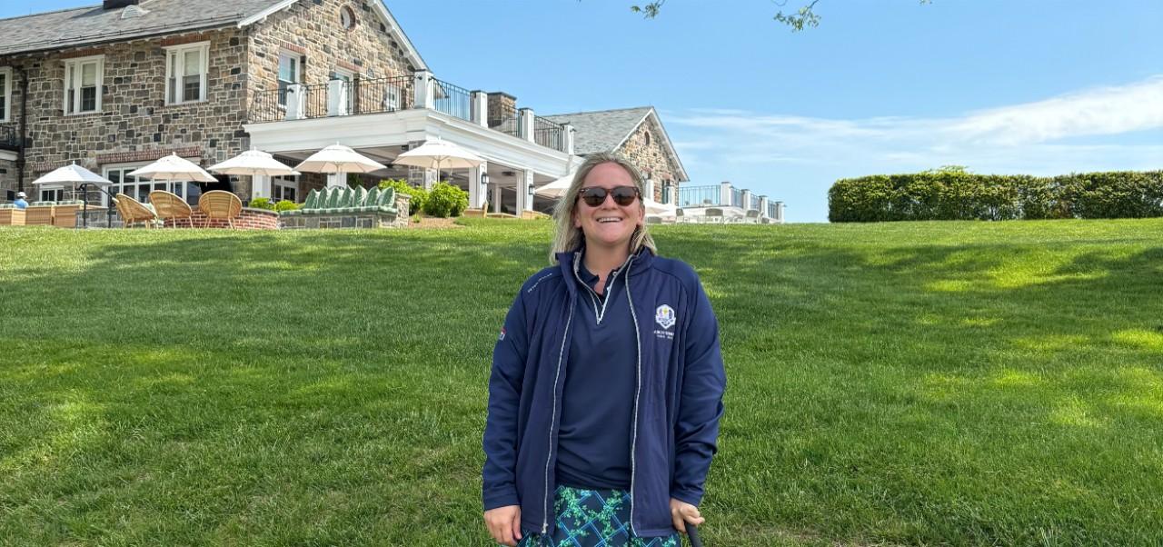 Caroline Kasper, NYU SPS Preston Robert Tisch Institute for Global Sport alumnus, smiles for the camera while standing on a grassy hill at a historic resort.