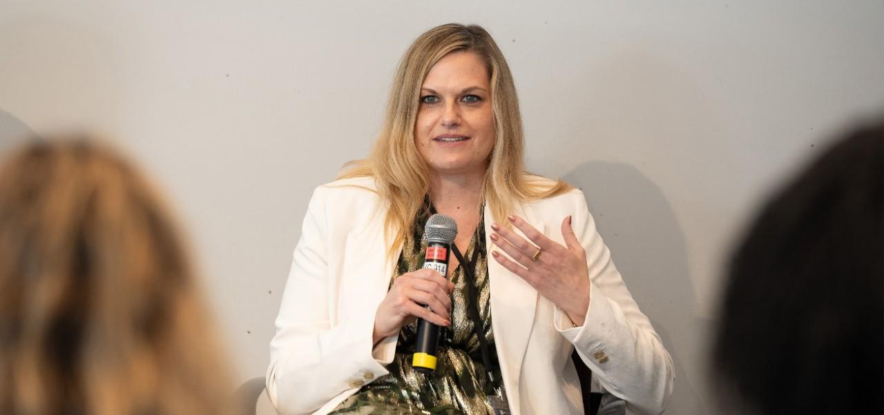 Cathy Merritt, Division of Programs at NYU SPS alumnus, addresses a crowd while holding a microphone.