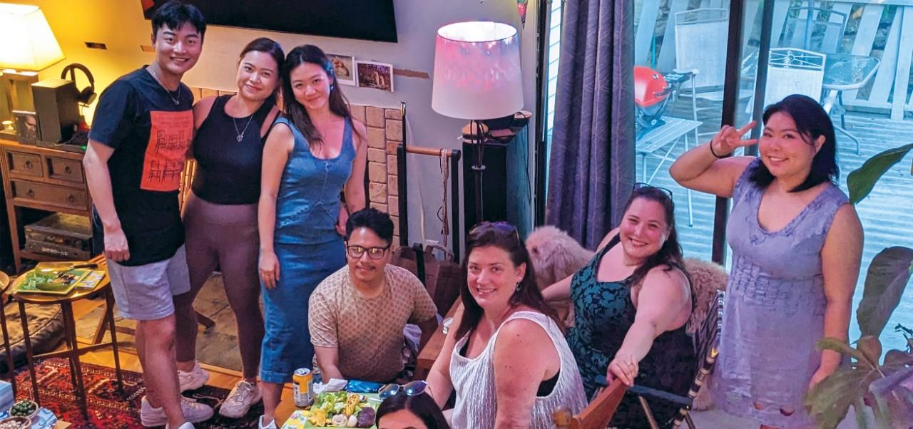 Eva E. K. "EEK" Castleton poses for a photo with a diverse group of friends in a cozy living room.