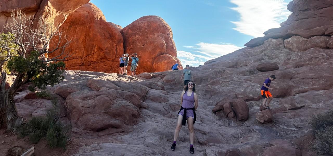 Jessica Blodgett, NYU SPS Division of Programs in Business alumnus, smiles for the camera while standing between dramatic boulders and cliff faces.