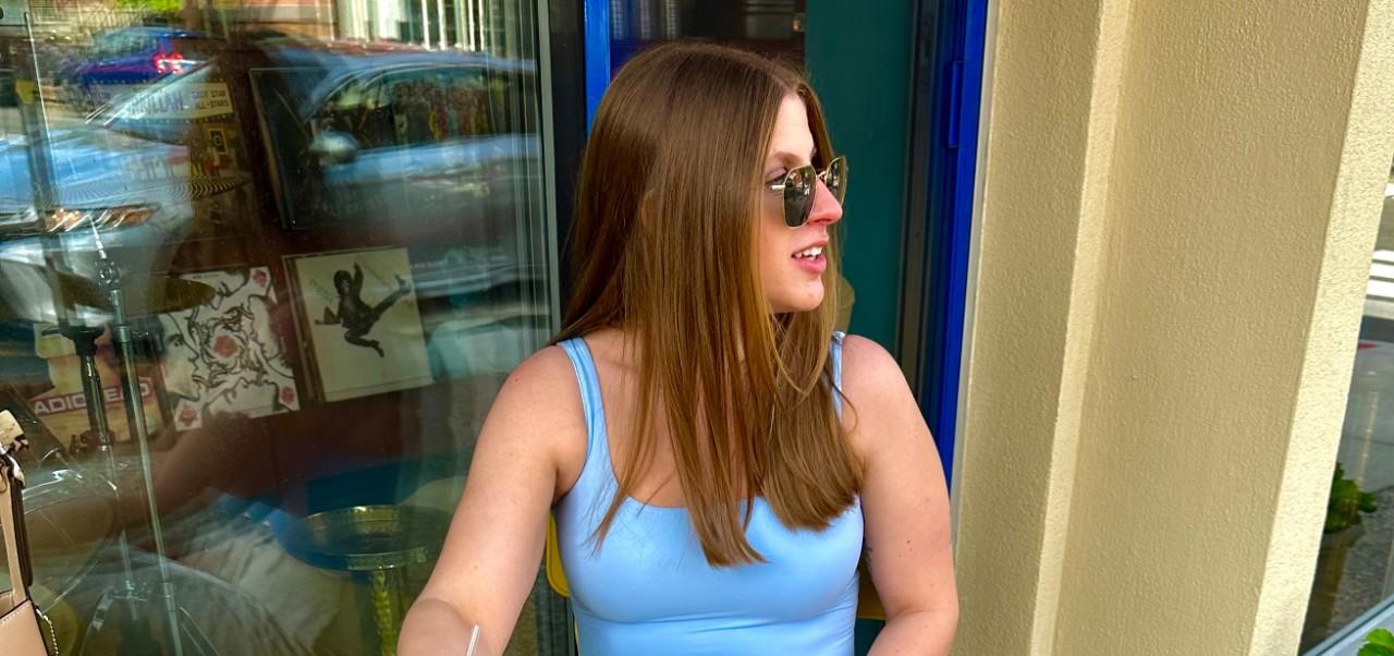 Rebecca Bodtmann, Preston Robert Tisch Institute for Global Sport alumni at NYU SPS, looks off to the right of the camera while wearing sunglasses and seated.