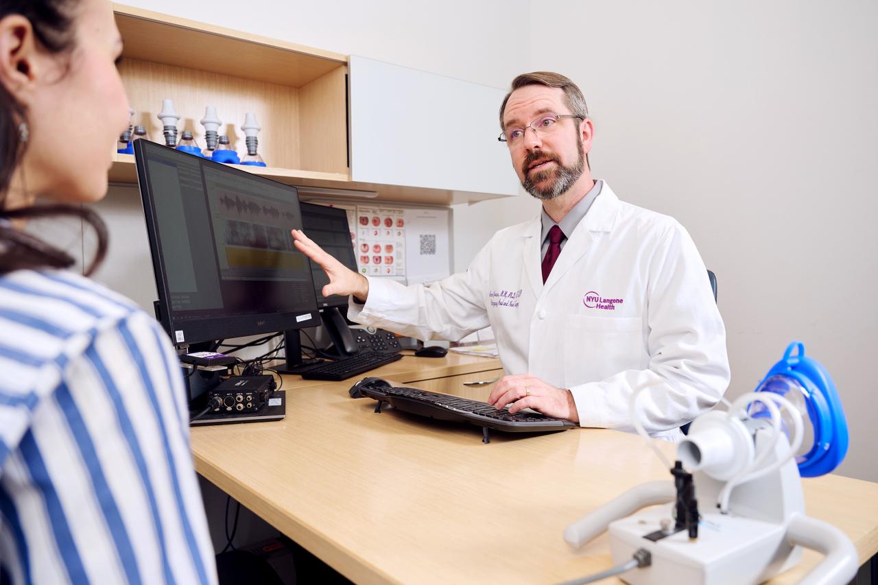 NYU SPS Certificate in Vocology instructor Aaron Johnson gestures toward a computer screen while giving a consultation in his office