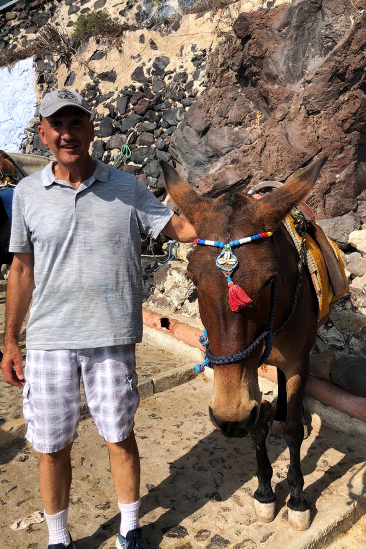 Continuing Education professor Samuel Sultan poses for a photo with a donkey while traveling