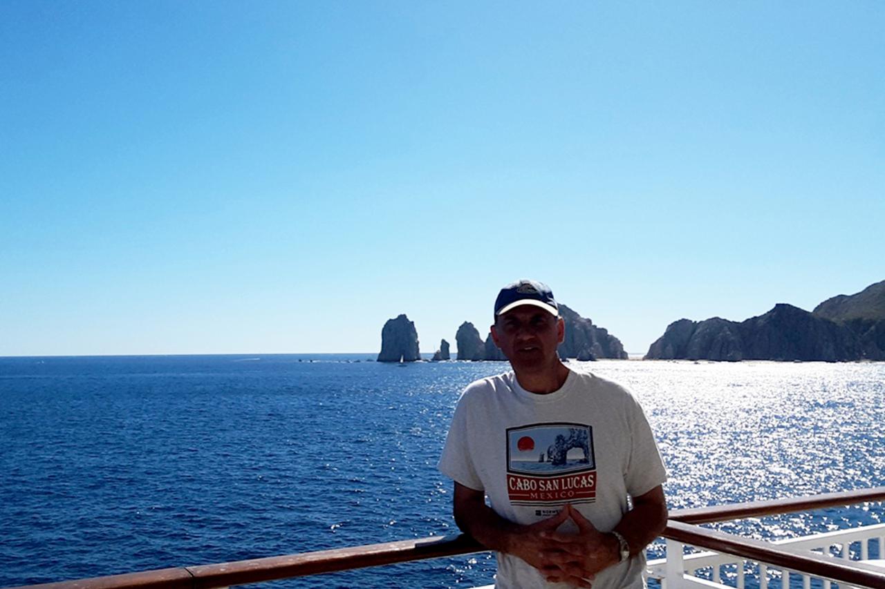 Continuing Education professor Samuel Sultan poses for a photo on a terrace in front of the Pacific Ocean