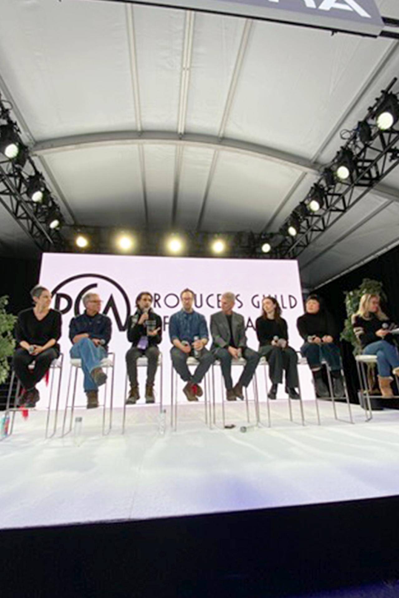 NYU SPS CE instructor Simon TaufiQue sits in a chair on a stage next to colleagues on a panel at a Producers Guild of America event