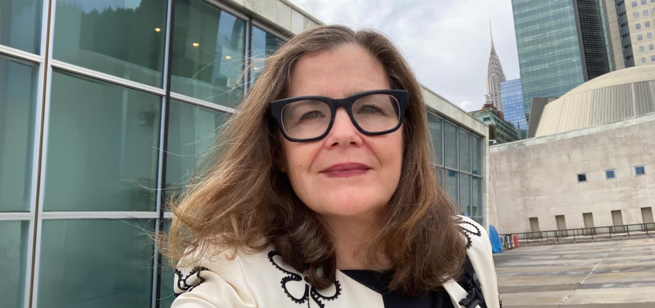Anne Marie Goetz wears a white jacket while posing for a selfie outside of the United Nations before an event in NYC