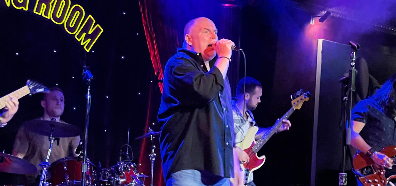  Band: Kenneth A Kerrigan, Adjunct Instructor, Marketing and Public Relations, Division of Programs in Business, NYU SPS, sings on stage with a band.