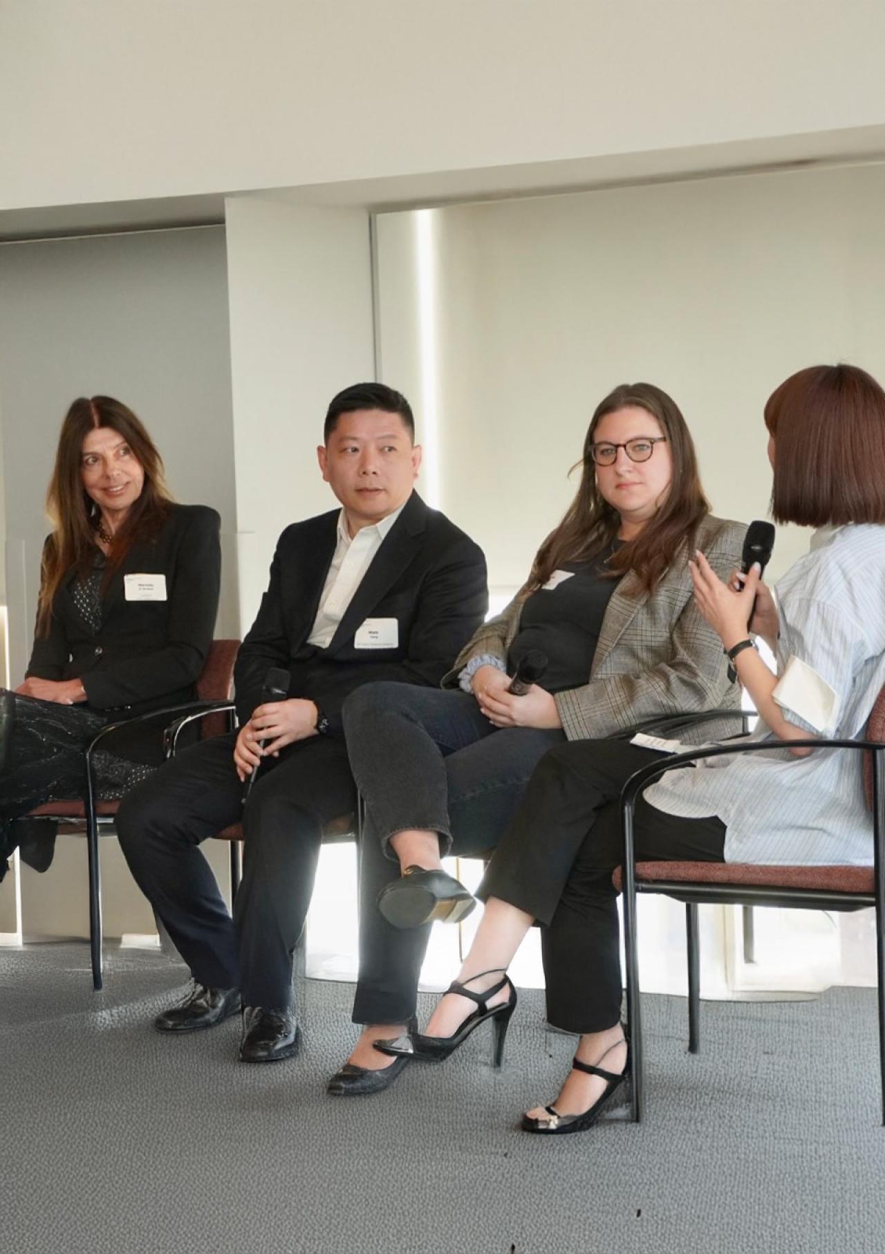 Marcela Berland sits with a group of fellow panelists dressed in business attire.