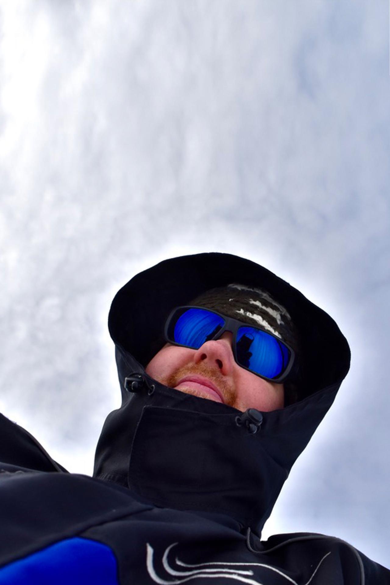 Nicholas Reese takes a selfie while wearing winter gear with the cloudy sky behind him