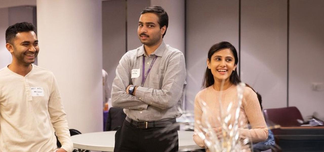 NYU SPS student Chaithanya Bhathi smiles at an event in a classroom with two other students