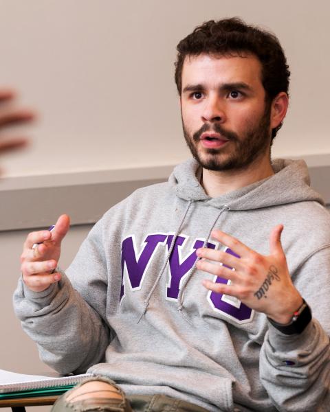 An NYU SPS student wearing a grey NYU hoodie talks during class while completing his undergraduate degree