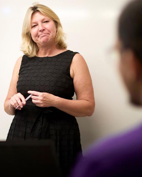 Faculty member stands in front of an audience.
