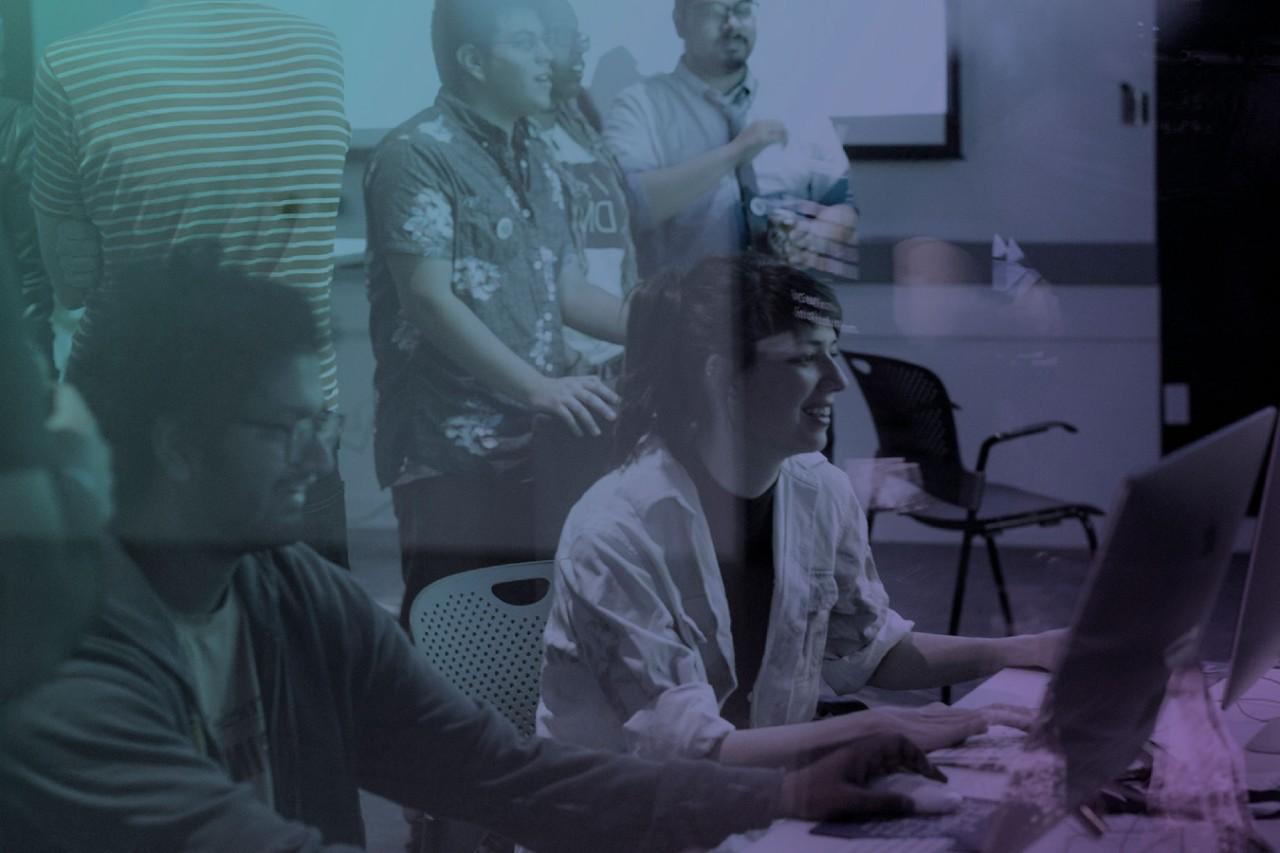 A photo of NYU SPS students in a classroom, some sitting at a table and some standing, is overlaid with a blue and purple gradient