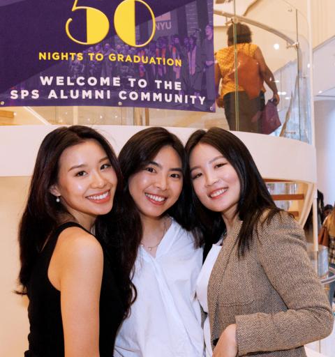 Three alumni smiling at an alumni event.