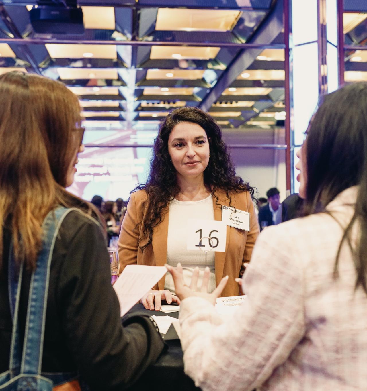 Three female NYU SPS students meet and greet each other at a career networkign event.