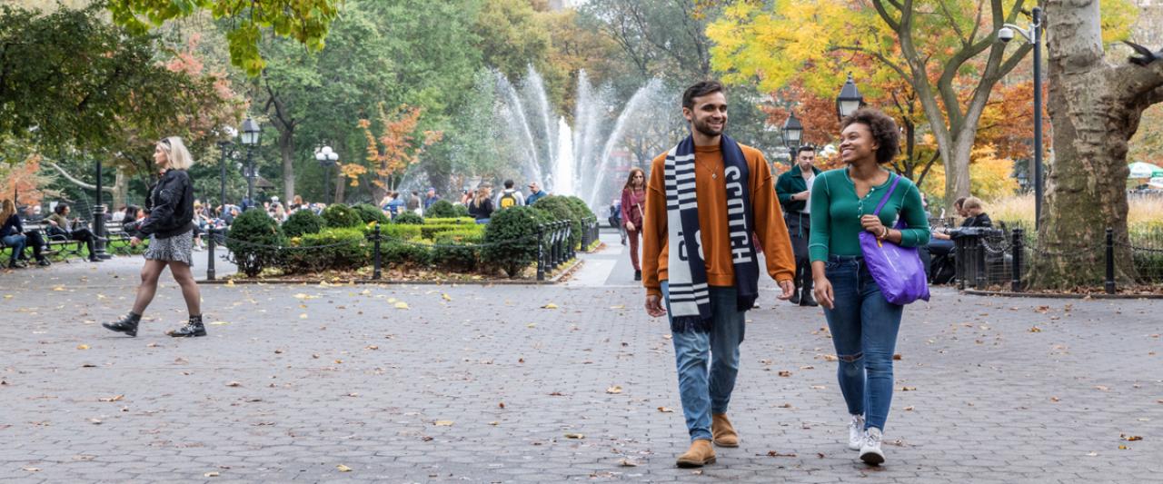 Two NYU SPS students walk together in Central Park in the fall.