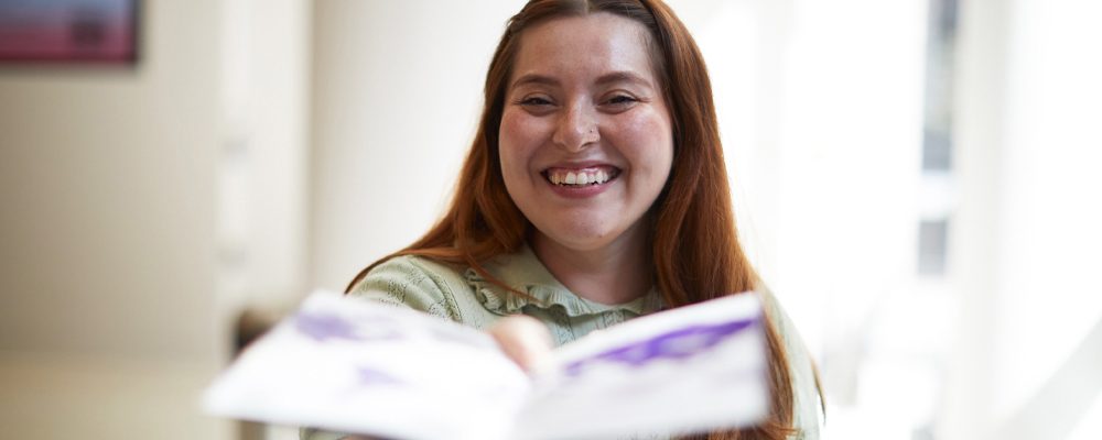 Woman smiles as she passes out an admissions brochure